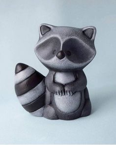 a ceramic raccoon figurine sitting next to an egg on a white background