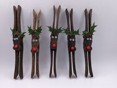 four wooden sticks with reindeer heads and holly leaves on them, lined up against a white background