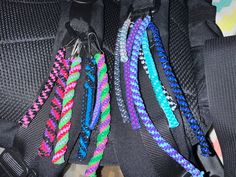 several different colored bracelets hanging from the back of a backpack