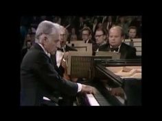 an old man playing the piano in front of other men wearing tuxedos and suits