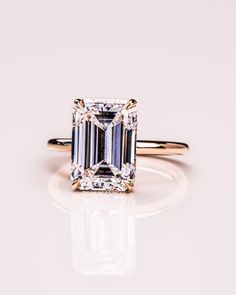 an emerald cut diamond ring on a white surface