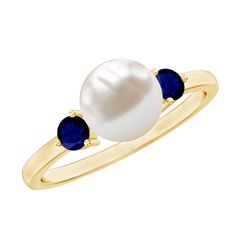 a white pearl and blue sapphire ring on a yellow gold plated ring with two stones