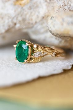 a close up of a ring with a green stone on it's side and some white stones in the background