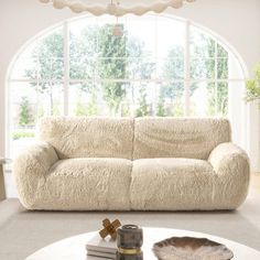 a living room filled with furniture and a white table in front of a large window