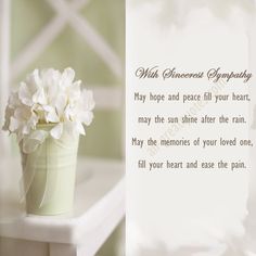 a vase filled with white flowers sitting on top of a table next to a card