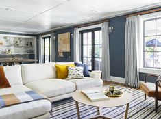 a living room with blue walls and white couches, striped rugs and chairs