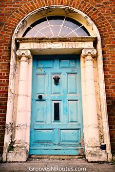 an old blue door in front of a brick building with arched window and stone arch