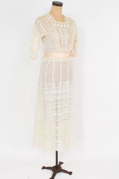 "~ 1900s beautiful tiered ivory lace sheer dress ~ Delicate pretty vintage dress ~ Perfect for a wedding dress ~ Sheer netting, insertion lace ~ 2 layer skirt ~ 28\" Peach satin waist sash ~ 2 \" peplum at waist ~ Back buttons and snaps Condition: Good but there are couple places with tiny holes. Priced accordingly Bust- 34\" (86.5 cm) Shoulder- 16.5\" (42 cm) Sleeve- 11\" (26 cm) Waist- 24\" (61 cm) Hips- 48\" (122 cm) Length Top skirt- 49\" (124.5 cm) Length under skirt- 51\" (129.5 cm) More I Victorian Dress With Lace Bodice, Vintage Lace Wedding Dress With Patchwork, Sheer Cream Lace Dress, Vintage Victorian Dress With Lace Bodice, Vintage Lace Patchwork Wedding Dress, Victorian Lace Dress With Delicate Details, Victorian Cream Dress With Lace Trim, White Lace Vintage Dress For Garden Party, Elegant Victorian Lace Dress For Garden Party