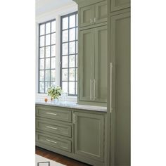 a kitchen with green cabinets and white counter tops