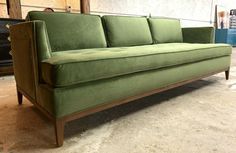 a green couch sitting on top of a hard wood floor