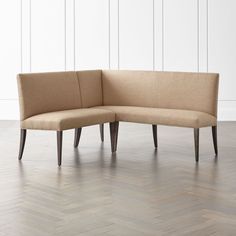 a corner couch sitting on top of a hard wood floor next to a white wall