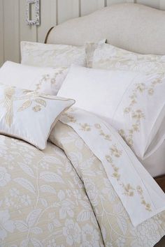 a bed with white and gold comforters in a bedroom next to a headboard