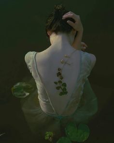 the back of a woman's body in water with lily pads on her neck