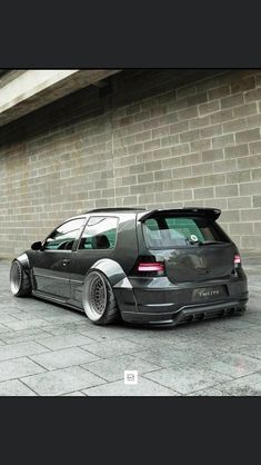 a black car parked in front of a brick wall