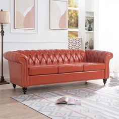 an orange leather couch sitting on top of a wooden floor next to a white rug