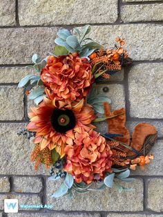 an arrangement of flowers and leaves on a brick wall