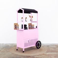 a pink cart sitting on top of a floor next to a white wall and wooden floors