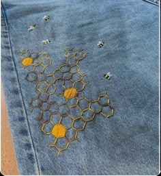 embroidered honeycombs and bees on blue jean jacket with yellow stitching in the middle