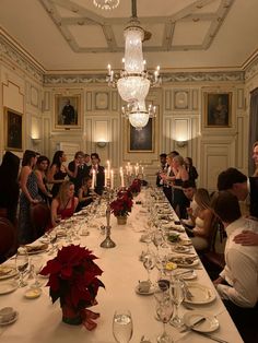 a group of people sitting around a long table with plates and silverware on it