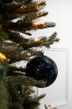 an ornament hanging from the top of a christmas tree in front of a door