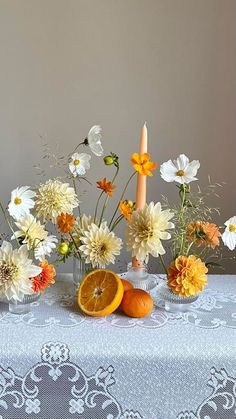 an arrangement of flowers, oranges and candles on a table