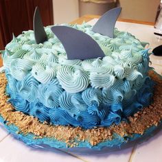 a blue and white cake with a shark fin on it's top sitting on a table