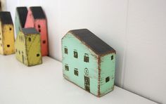 small wooden houses are lined up on the wall next to each other, painted in different colors