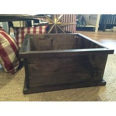 a wooden box sitting on top of a floor next to pillows and a tablecloth