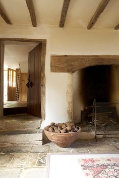 a bowl filled with wood sitting on top of a floor next to a fire place