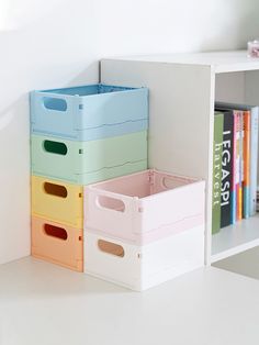 four plastic storage boxes sitting on top of a white shelf next to a bookshelf