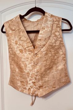 Step back in time with this exquisite piece of Victorian history--a gentleman's wedding waistcoat, dating back to 1855. This hand-stitched vest was crafted with meticulous attention to detail, featuring a luxurious cream silk brocade front and a durable linen/cotton back. The waistcoat is adorned with five fabric-covered buttons and a rounded collar, epitomizing the elegance and refinement of the Victorian era. Key Features: * Material: Warm golden-cream silk brocade front, linen/cotton back * Details: Five fabric-covered buttons, rounded collar * Fit: Adjustable back with two fabric tabs, three metal eyelets per side, and lacing for a perfect fit * Size: Chest 27", Length 19" (Smallish size) * Provenance: Handwritten tag indicates this waistcoat was worn at Grandpa Price's wedding in 1855 Victorian History, Mens Wedding Suits, Wedding Waistcoats, Victorian Gentleman, Cream Silk, Silk Brocade, Wedding Suits Men, Fabric Covered Button, Back In Time