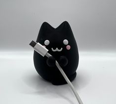 a black cat plugged in to an iphone charger with a white cord attached