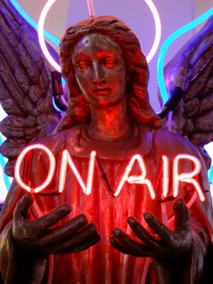 a neon sign that reads on air with an angel holding hands in front of it