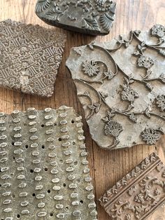 four decorative pieces of metal sitting on top of a wooden table next to each other