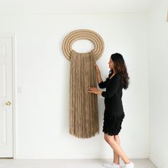 a woman standing in front of a rope sculpture