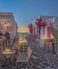 an outdoor dining area with tables, chairs and candles lit up at dusk on the beach