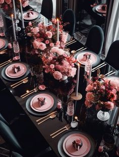 a long table with black chairs and pink flowers on it is set for an elegant dinner