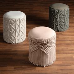 three stools with tassels on them sitting on a wooden floor next to each other