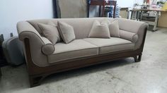 a beige couch with pillows on it in a room filled with furniture and other items