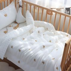 a baby crib with white sheets and pillows