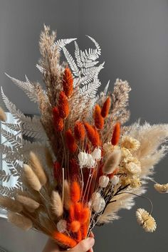 a person holding a bunch of dried flowers in their hand with the sun shining on them