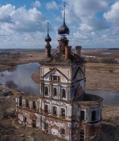 an old building with two towers in front of a body of water and cloudy sky