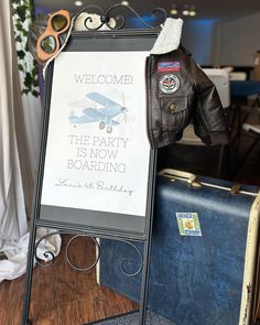 a welcome sign with a jacket and sunglasses on it next to suitcases in a room