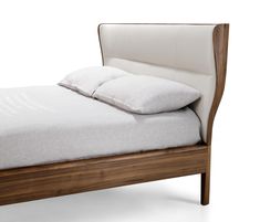 a bed with white sheets and pillows on it's headboard, against a white background