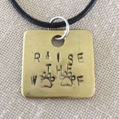 a dog tag with the words raise the wolf written on it and two paw prints