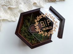 an award is placed in a small wooden box on a white surface with greenery