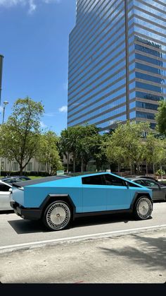 a blue car is parked on the side of the road in front of some tall buildings