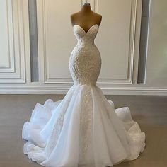 a wedding dress on display in front of a white wall