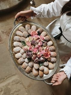 a woman holding a platter full of cookies and flowers