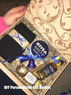 a person is holding a wine and chocolates in a gift box with a blue ribbon